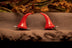 A pair of red devil horns hair clips placed on a textured surface with a neutral background.