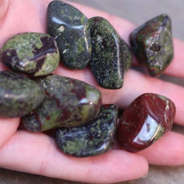 Hand holding a collection of green and brown stones