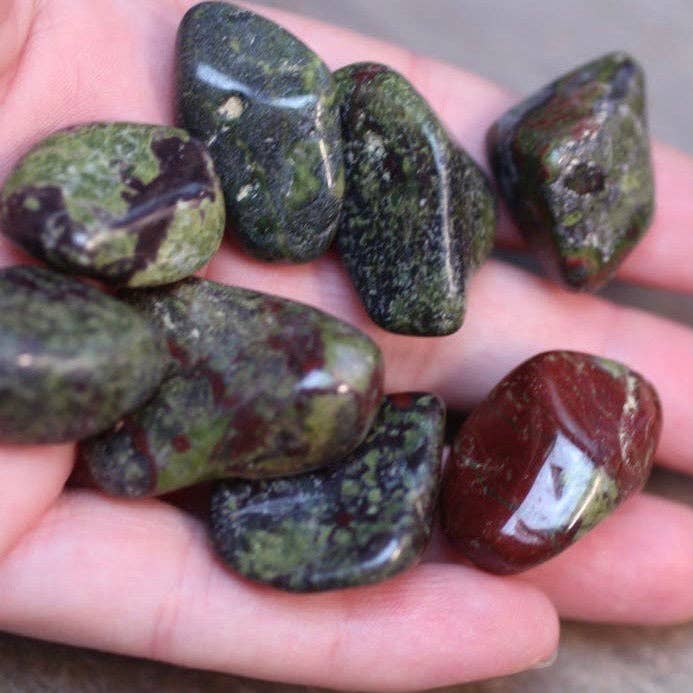 Hand holding a collection of green and brown stones