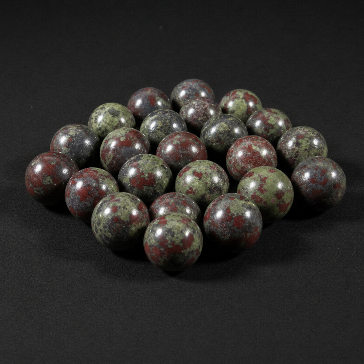 Alternate view of polished green, red, and gray Dragon Stone mini spheres on a matte black background
