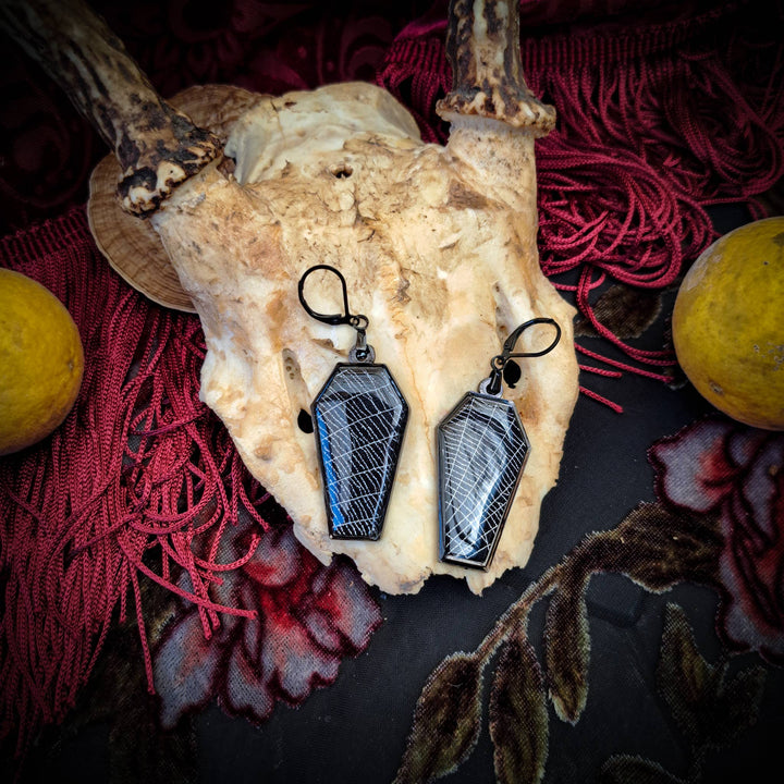 Side view of black coffin-shaped spiderweb earrings