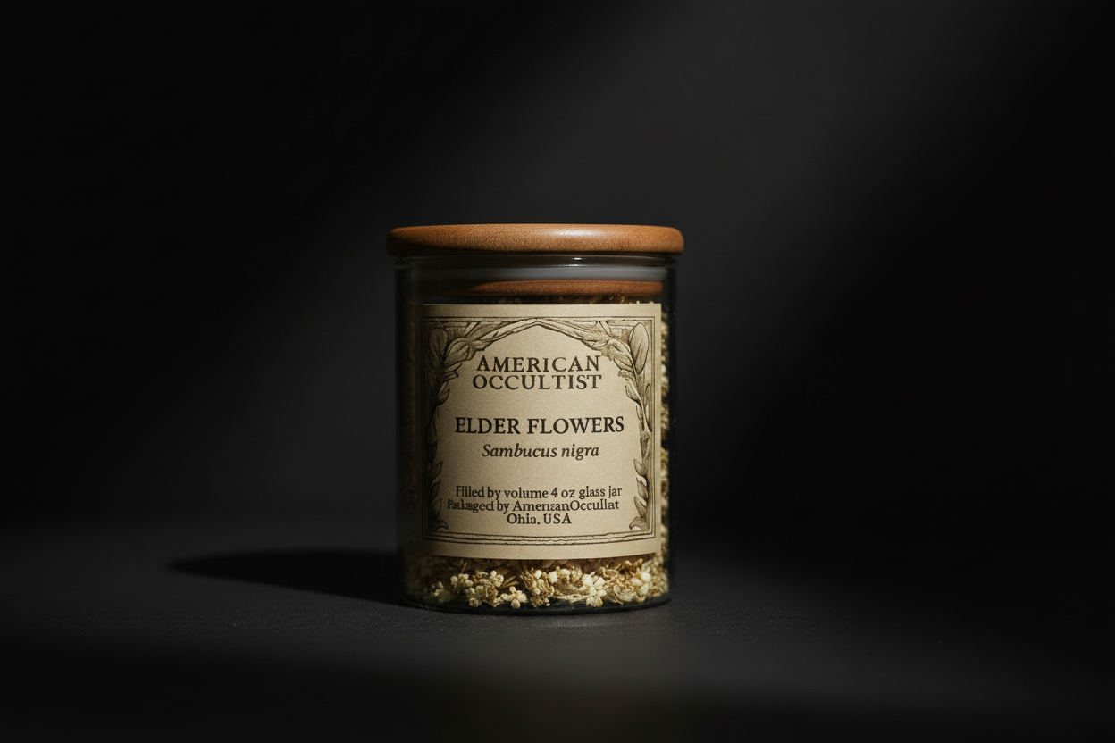 Jar of 'American Occultist Elder Flowers' on a wooden table with candles, stones, and books in a mystical setting.