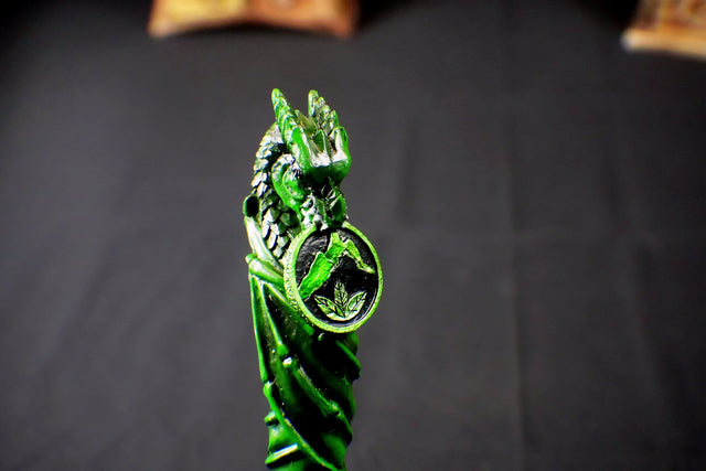 A green wand sculpted in the form of a dragon with scales and a ring detail, displayed against a dark background.