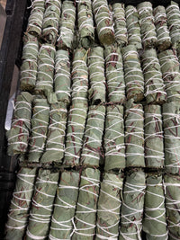 Stack of green rolled items tied with white string on a black surface