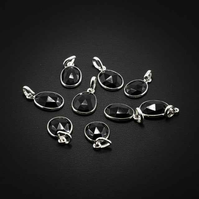 Black gemstone pendants with silver settings on a black background