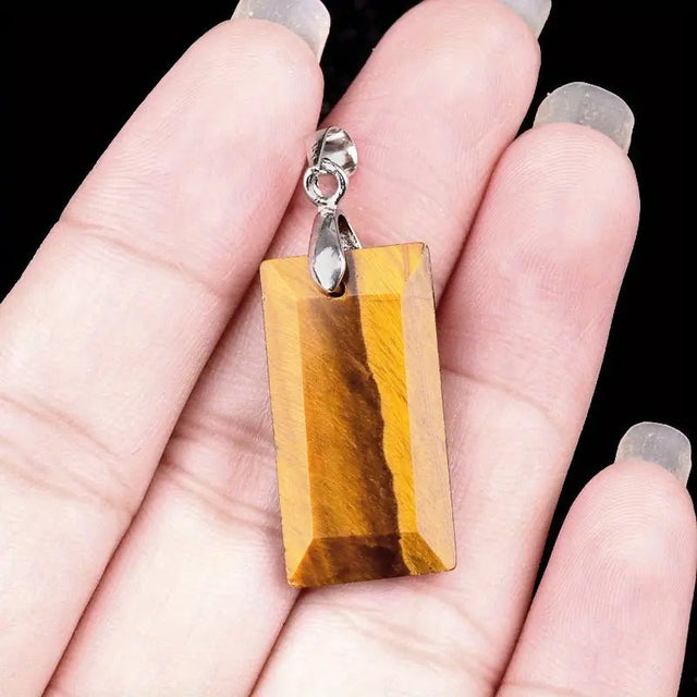 Tiger's eye pendant on a hand with a black background