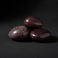Three polished deep crimson garnet palm stones arranged on a matte black surface