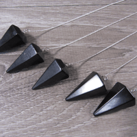 Black pyramid-shaped pendants on a silver chain on a wooden surface