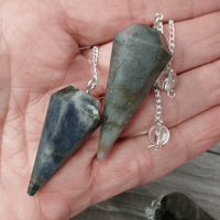 Two stone pendants on silver chains held in a hand.