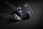 Purple pointed pendulum with chain shown in hand