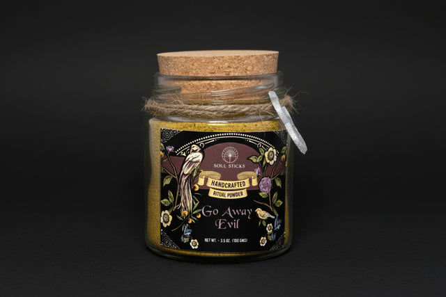 Jar of 'Go Away Evil' ritual powder with decorative label and cork lid on a white background