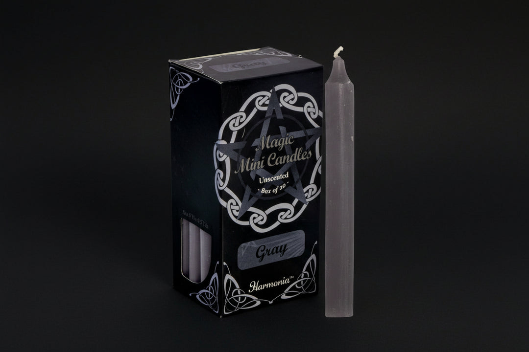Gray candle next to its packaging with &