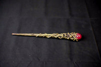 Decorative wand with a red gem on a black background