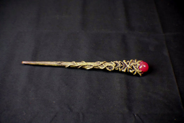 Decorative wand with a red gem on a black background