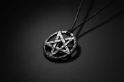 Pentagram pendant on a cord against a wooden background