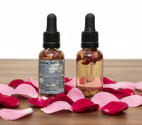 Two bottles of 'Healing Spell Oil' by Belladonna Botanicals on a wooden surface with pink and red rose petals.