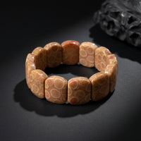 Representative stretch bracelet sold as Coral Jade with polished ornamental-material beads; material, color, pattern, bead size, treatment, cord tension, and fit vary