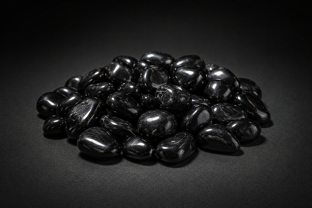 Pile of polished black stones sold as Jet with soft glossy highlights on a matte black surface