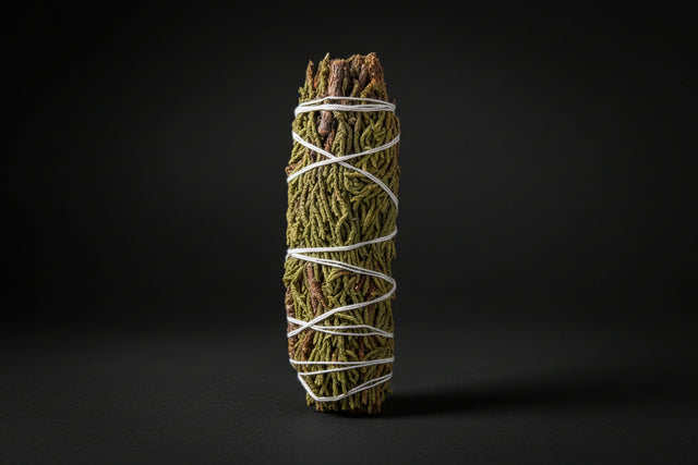 Bundled juniper smoke-cleansing wands tied with twine on a white background