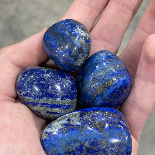 Hand holding four blue and green marbled stones