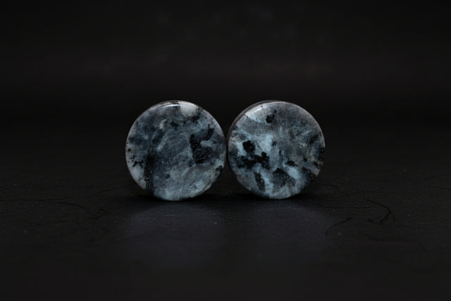 Representative double-flare plug pair sold as Larvikite; rock identity, treatment, selected size, silver-blue schiller, grain pattern, polish, and exact condition vary