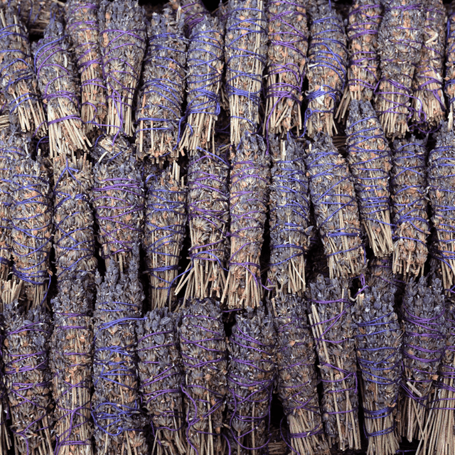 Bundles of lavender smudge sticks tied with purple ribbons.