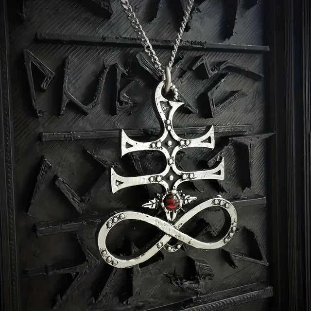 Silver pendant sulfur cross with a red gemstone on a dark background