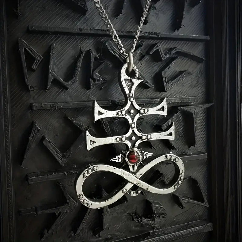 Silver pendant sulfur cross with a red gemstone on a dark background
