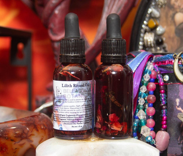 Two bottles of Lilith Ritual Oil on a decorative background with colorful beads and a statue.