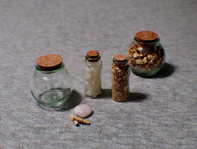 Set of small glass jars with cork lids on a textured surface