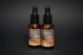 Two bottles of Locifer Ritual Oil with botanicals on a dark background