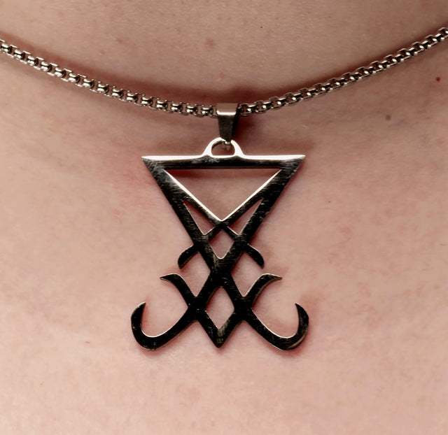 silver lucifer pendant on a metal chain around a neck