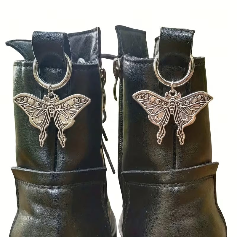 Pair of silver-tone lunar moth boot charms clipped to black boots