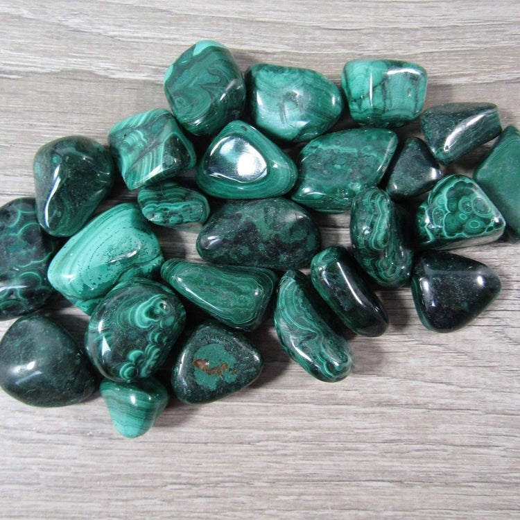 Collection of green tumbled stones on a wooden surface