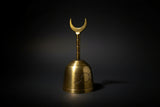 Gold bell with a crescent moon design on a dark background