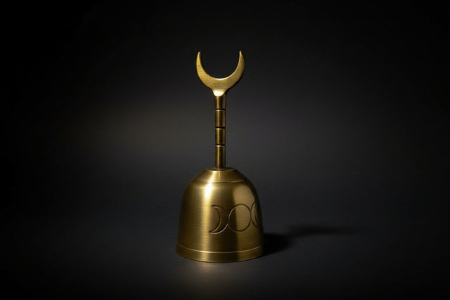 Gold bell with a crescent moon design on a dark background