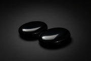 Two polished black obsidian palm stones held in a hand