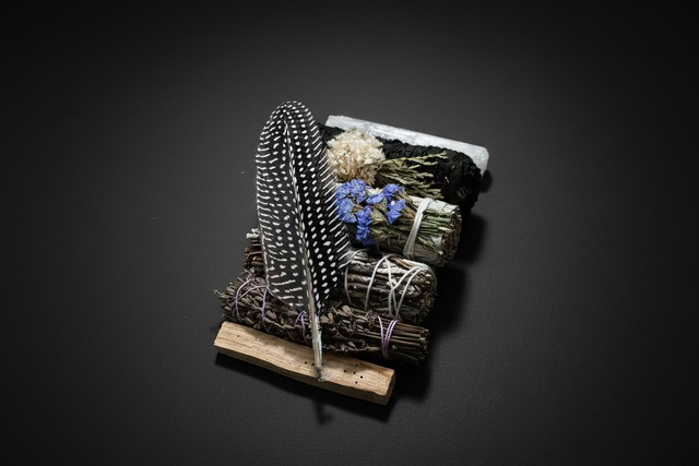 Decorative bundle with feathers and flowers on a dark background