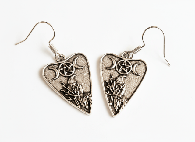 Heart-shaped silver earrings with intricate designs on a white background