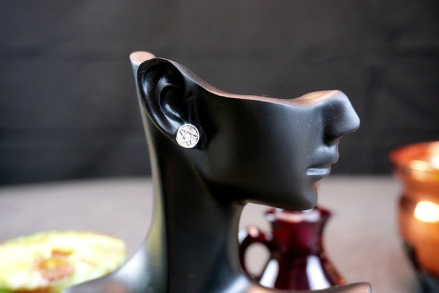 Black earring holder shaped like a face with an earring on a blurred background