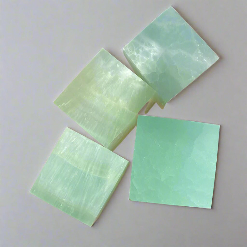 Four green soap bars held in a hand with a leafy background
