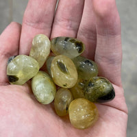 Hand holding a collection of green and black stones