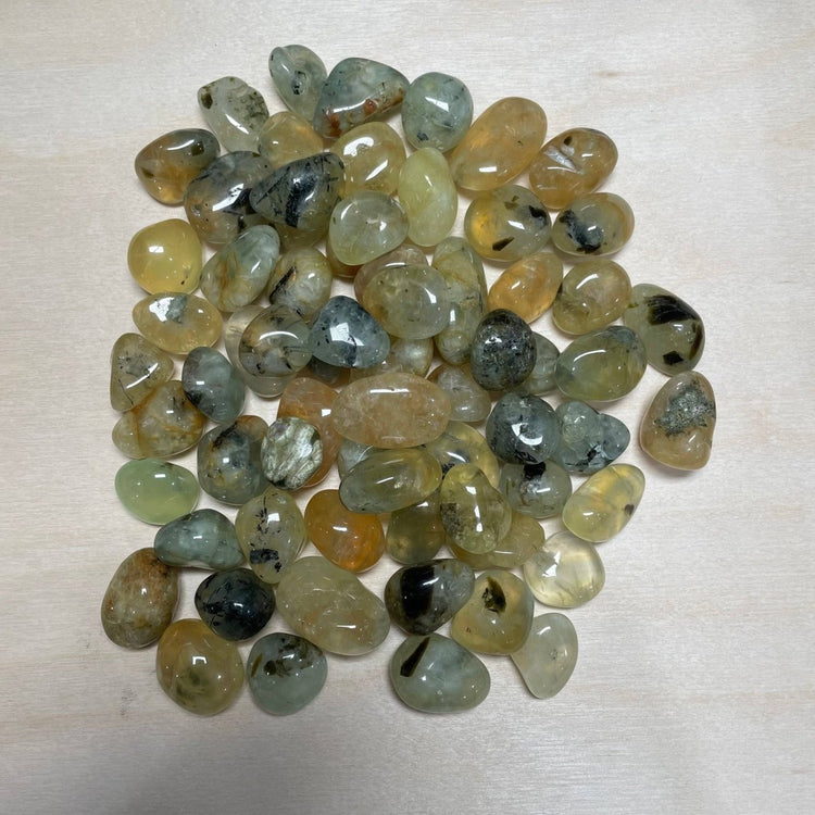 Collection of multicolored gemstones on a light wooden surface