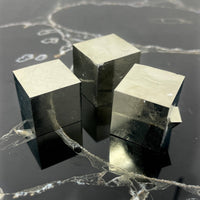 Three metallic cube blocks on a reflective black surface