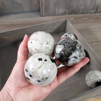 Hand holding three crystal balls with a wooden tray in the background