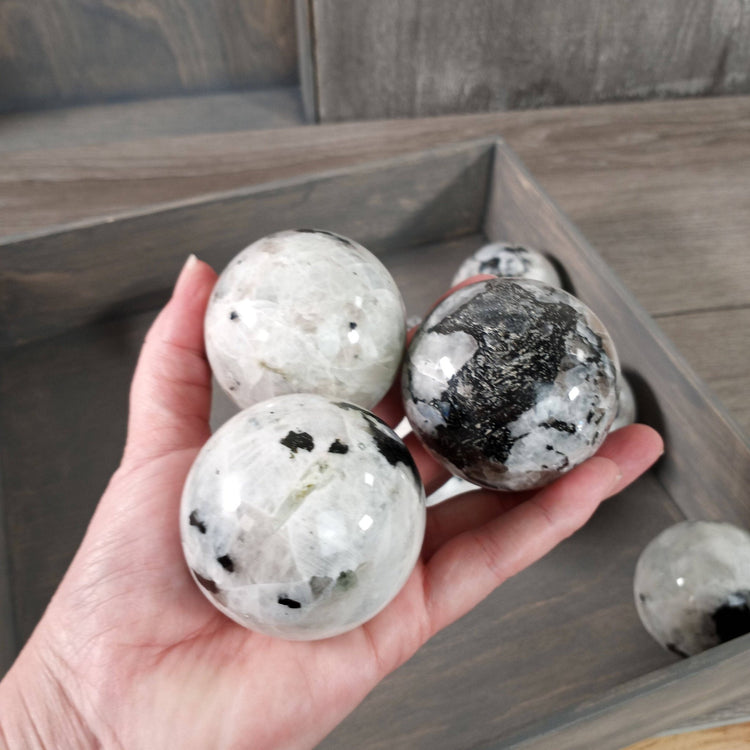 Hand holding three crystal balls with a wooden tray in the background