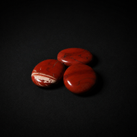 Alternate view of three polished red jasper palm stones on a matte black background