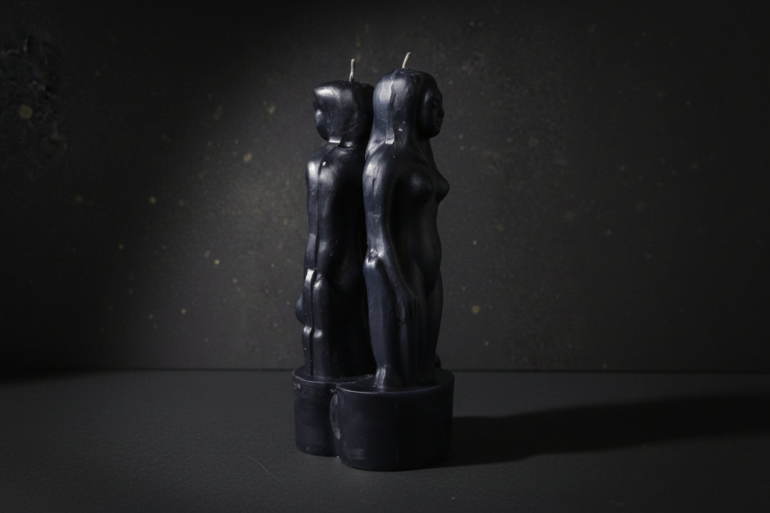 Black paired-figure separation ritual candles on a dark background