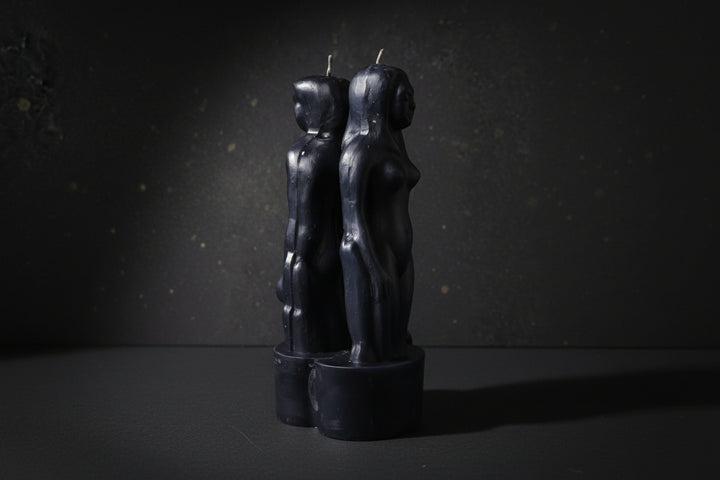 Black paired-figure separation ritual candles on a dark background