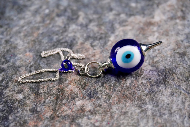 Blue evil eye charm necklace on a textured stone background